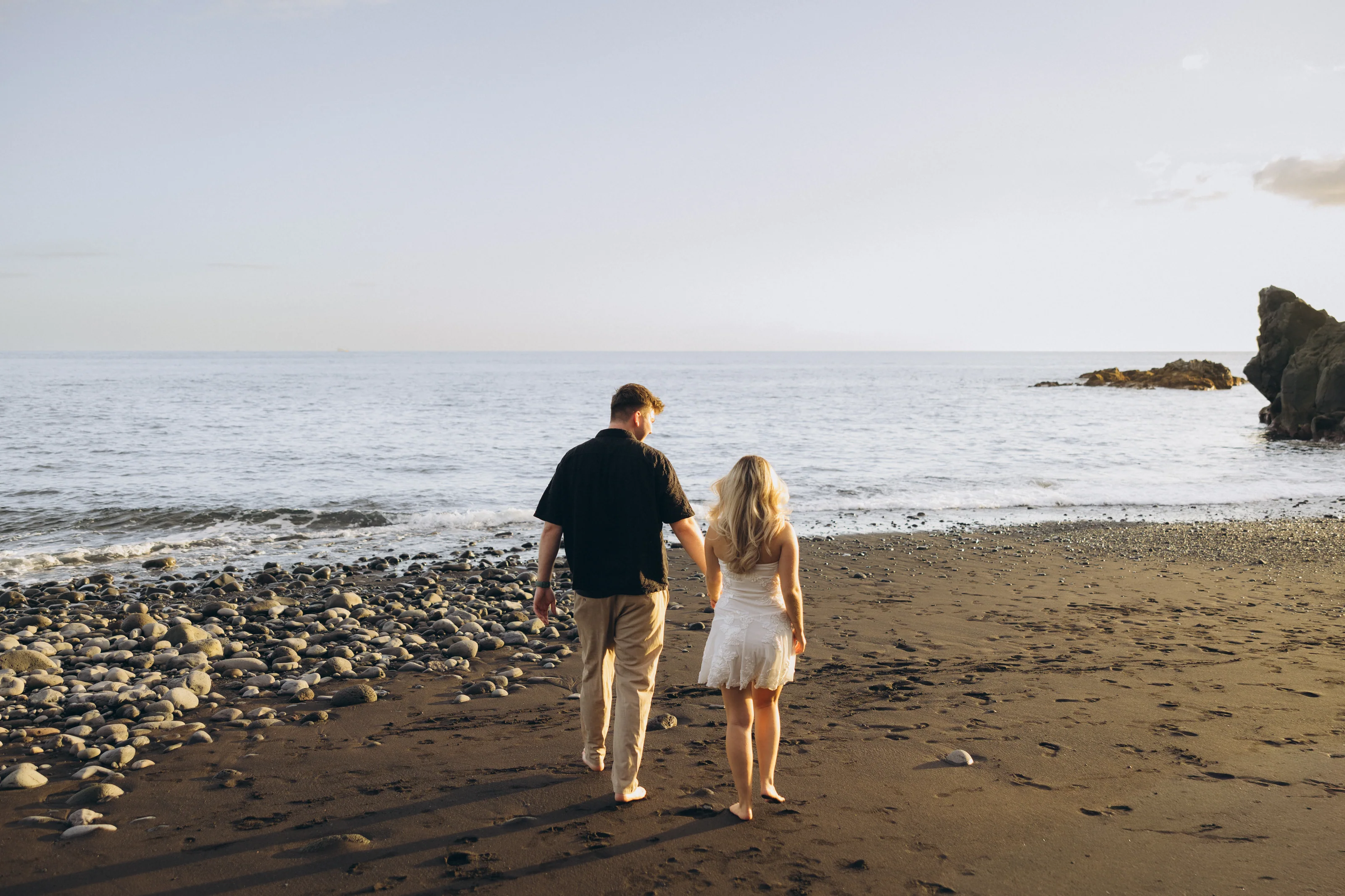Rebecca and Jake walking together on the beach at sunset