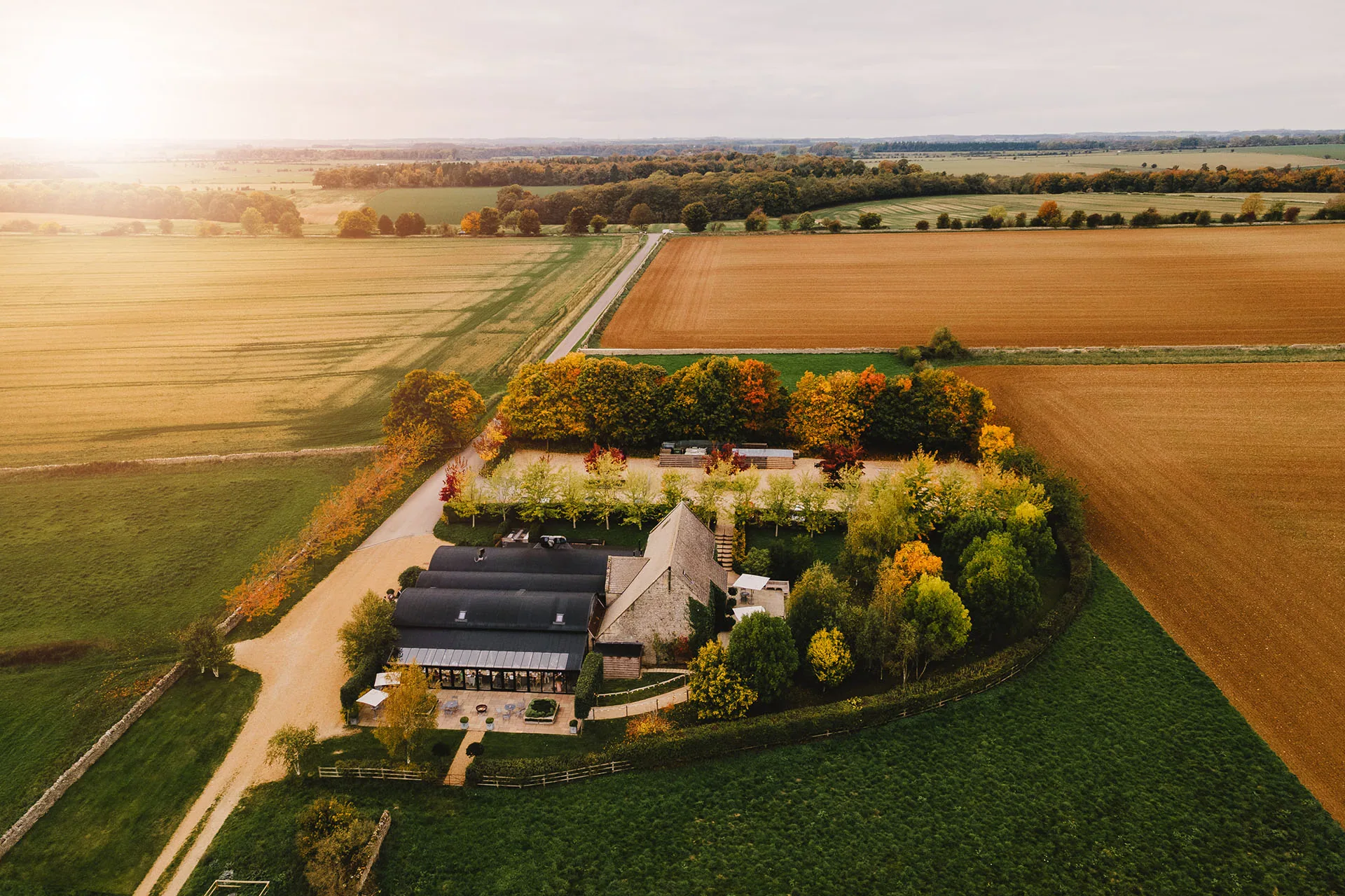 Stone Barn from the air, surrounded by Cotswold fields at golden hour